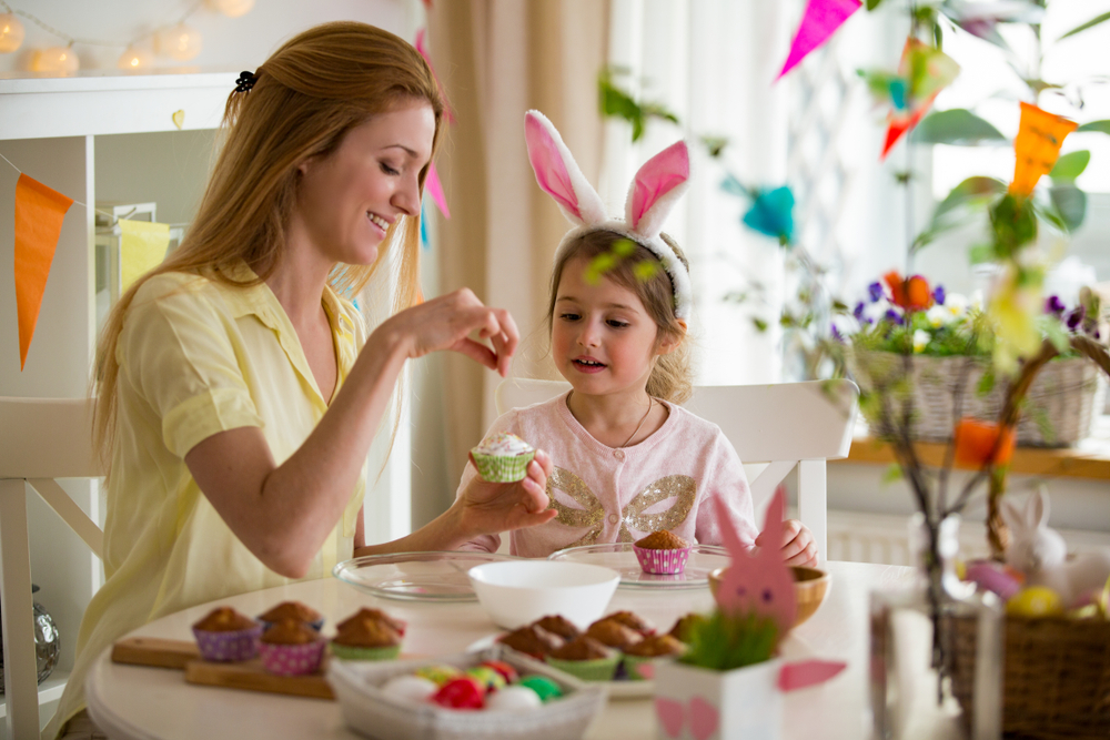 Kind met moeder maakt muffins tijdens Pasen